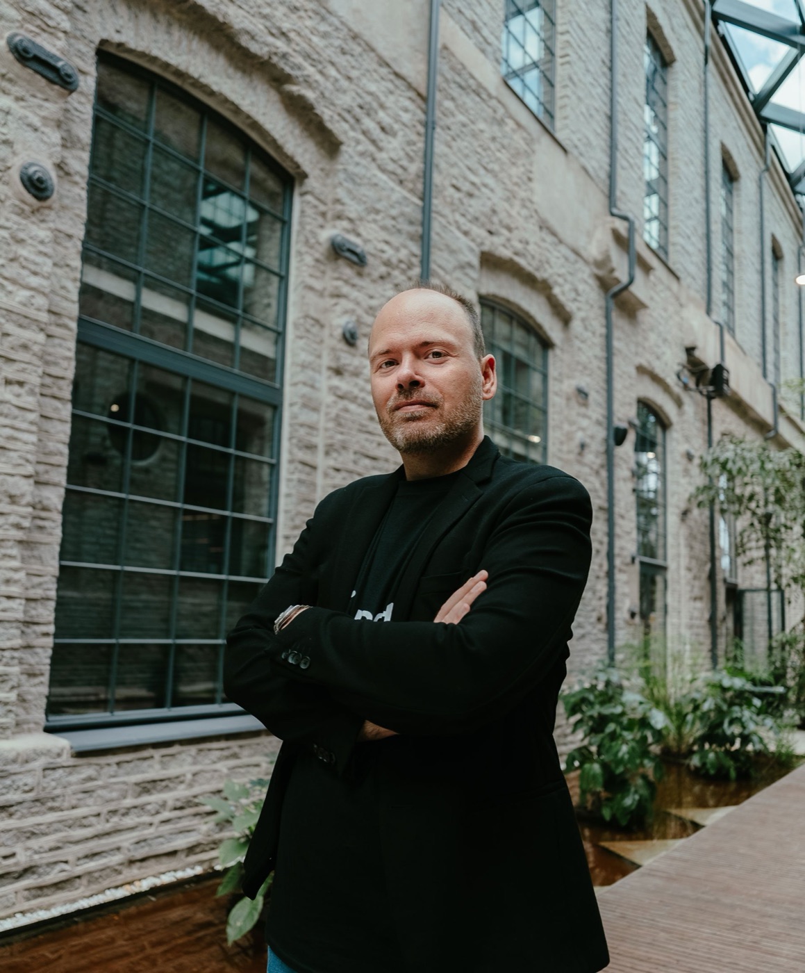Kevin Murcko, arms crossed, in a brick courtyard